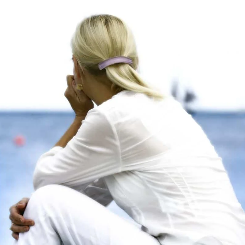 Vrouw zittend aan het water in reflectie. Beeld van rust en helderheid bij het terugvinden van richting.