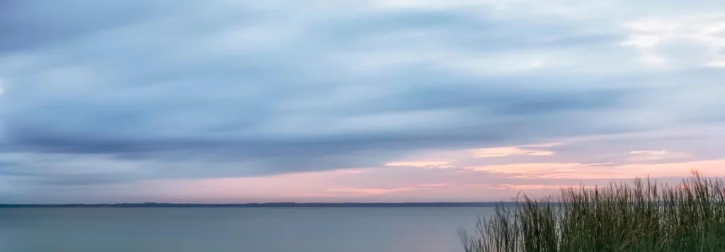 Stil landschap met kalm water en zachte horizonkleuren. Beeld van helderheid en herstel tijdens 1-op-1 trajecten.