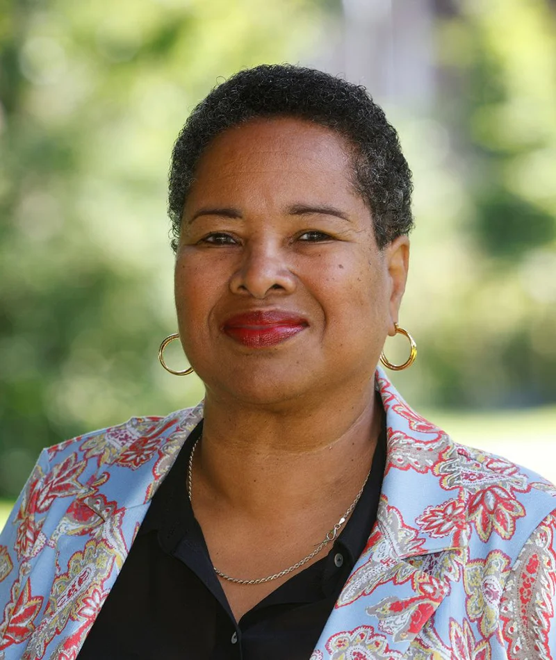 Sharon Burgler, executive coach en psycholoog, gefotografeerd buiten met rustige uitstraling. Symbool voor helderheid en vertrouwen bij Manitu.